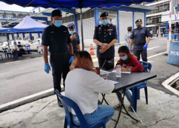 SHAMSUL Amar (kiri) membuat tinjauan orang ramai yang sedang mengisi borang permohonan rentas negeri di pintu pengawal, IPD itu hari ini.-UTUSAN/NOR AZIHAN GHAZALI