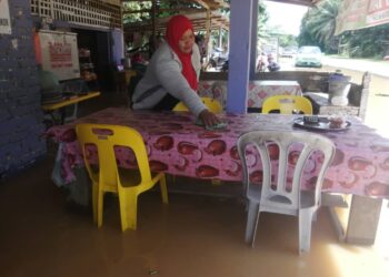 ENGKU Hasmah Engku Kamaruzaman, 45, masih meneruskan perniagaan kedai runcit dan makanan paginya seperti biasa walaupun kedainya di Kampung Nibong, Hulu Terengganu, Terengganu dinaiki banjir. -UTUSAN/ NOOR HAYATI MAMAT