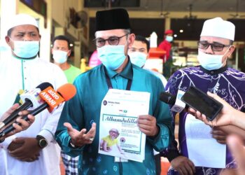 KAMARUDDIN Sedik (tengah) menunjukkan poster jelik memaparkan gambar Presiden Pas yang disunting pihak tidak bertanggungjawab selepas membuat laporan polis di Balai Polis Ayer Keroh, Melaka, hari ini. UTUSAN/ RASUL AZLI SAMAD