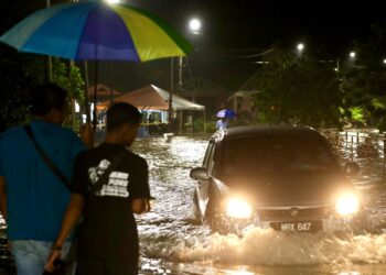 PENDUDUK di Taman Tuah Perdana bergegas mengalihkan kenderaan masing-masing selepas banjir mula melanda kawasan perumahan itu malam tadi ketika tinjauan dilakukan di Jasin, Melaka. UTUSAN/ RASUL AZLI SAMAD