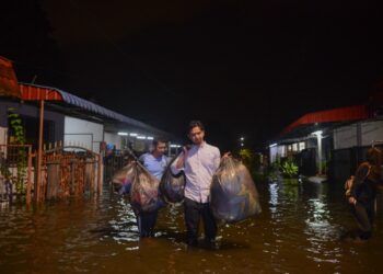 ROSYAM Abu (kanan)  menyelamatkan barang-barang setelah rumah sewa mereka dinaiki air di Kuala Nerus, Terengganu, malam tadi.