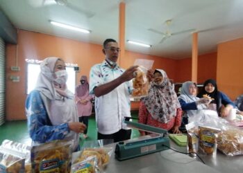 ROSOL (dua, kiri) melihat bungkusan kerepek diusahakan Siti Hadijah Yusoff di bengkel perusahaan di Kampung Teris di Hulu Terengganu hari ini. -UTUSAN/NOOR HAYATI MAMAT