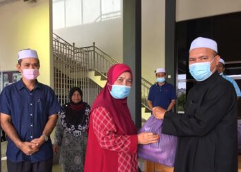 ISMAIL Ibrahim (kanan) menyampaikan bantuan kepada salah seorang penerima di Masjid Al-Hanan Simpang Empat, Tendong, di sini hari ini. -UTUSAN/ YATIMIN ABDULLAH