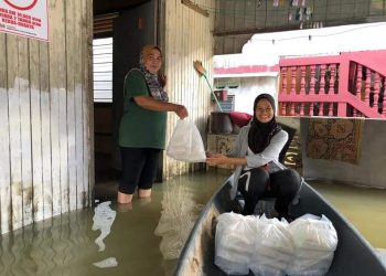 Makanan yang telah siap berbungkus diagihkan oleh sukarelawan menggunakan perahu secara terus kepada penduduk yang terkandas di rumah masing-masing di Rantau Panjang, Kelantan.-UTUSAN/ YATIMIN ABDULLAH