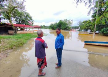 HANAFIAH Mat (kanan) ketika meninjau keadaan banjir di Kampung Tanjung di Kemaman hari ini.