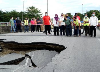 SAARANI Mohamad (depan) meninjau laluan yang rosak akibat banjir di Teluk Intan hari ini. - UTUSAN/ZULFACHRI ZULKIFLI