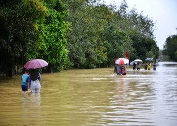 ORANG ramai meredah air banjir yang menenggelamkan laluan utama Kusial-Gual Ipoh di Tanah Merah hari ini.-UTUSAN/BAHRUDDIN HATTA