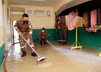 MOHD. Fazrul Azuan Norman (kiri) bersama anggotanya membersihkan kawasan rumah penduduk yang dilanda banjir di RPT Kampung Balun di Slim River hari ini. - UTUSAN/ZULFACHRI ZULKIFLI