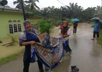 RUDIAH Jusoh (dua, kiri) bersama ahli keluarganya membawa permaidani miliknya yang dihanyutkan banjir di Kampung Baru Felda Neram 1 di Kemaman hari ini. - UTUSAN/NIK NUR IZZATUL HAZWANI NIK ADNAN