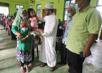 DR. Nik Muhammad Zawawi Salleh (berjubah) menyampaikan bantuan awal persekolahan kepada ibu bapa di Dewan Penggawa Daerah Semerak, Pasir Puteh, hari ini.-UTUSAN/TOREK SULONG