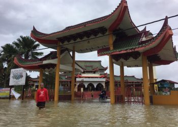 IMAM Masjid Jubli Perak Sultan Ismail Petra atau Masjid Beijing, di Rantau Panjang, Muhsin Abdullah berdiri di hadapan pintu gerbang masjid itu yang ditenggelami banjir hari ini. -UTUSAN/YATIMIN ABDULLAH