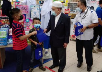 HANIFA Ahmad menyampaikan cenderahati kepada kanak-kanak sambil diperhati Adnan Abdul Rahman pada Program Walkabout Gerakan Pengguna Sempena Kempen Beli Barangan Malaysia, di sebuah pasar raya di Kota Bharu, semalam.-UTUSAN/ROHANA MOHD NAWI