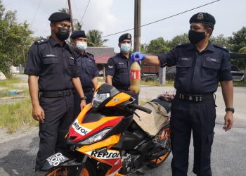 MOHD. Azmir Damiri (kanan) menunjukkan air ketum dan motosikal yang ditinggalkan seorang pemuda dalam Op Rentas Negeri di Kampung Golok, Pasir Puteh hari ini..-UTUSAN / TOREK SULONG