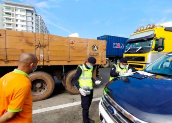 DUA anggota JPJ sedang mengeluarkan saman terhadap seorang pemandu lori dalam satu sekatan jalan raya (SJR) sempena 'Op Covid-19' berhampiran Plaza Tol Juru arah selatan, Butterworth, Pulau Pinang hari ini.