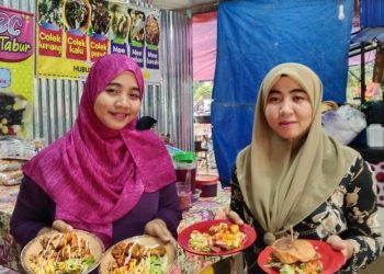 NOR NADIA Mohamad (kanan) dan kakaknya, Nurul Asyikin menunjukkan chicken chop yang dijual di gerainya pada harga RM10 untuk tiga set di Kampung Teluk Menara, Kuala Terengganu hari ini.-UTUSAN/NORADILA MAHAMAD