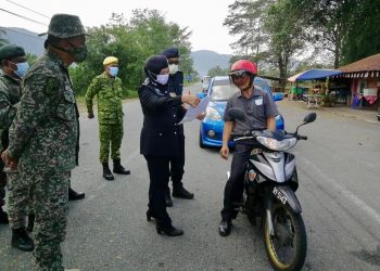 SURINA Saad memeriksa surat pengesahan majikan seorang penunggang motosikal di SJR 
Kaki Bukit, Jalan Kem Tasoh, Padang Besar, Perlis hari ini. - UTUSAN/NUR NAZLINA NADZARI