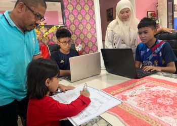 JULIANA dan suaminya, Maruwan Ahmad (kiri) melihat dua anaknya yang sedang mengikuti kelas dalam talian sementara seorang lagi sedang membuat kerja rumah di Sawah Sempadan, Tanjong Karang, Selangor baru-baru ini.