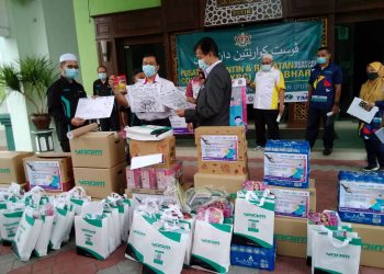 DR. ZAINI Husin (kanan) melihat buku mewarna untuk diagihkan kepada kanak-kanak yang ditempatkan di PKRC Putik, Pengkalan Chepa hari ini.-UTUSAN/ ROHANA MOHD NAWI