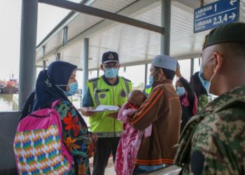 AHMAD Shukri Mat Akhir memeriksa surat kebemaran rentas daerah seorang penumpang feri ketika memantau pematuhan SOP di Terminal Feri Kuala Kedah, Alor Setar hari ini. UTUSAN/SHAHIR NOORDIN