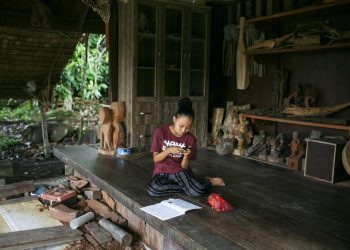 S. JERIKA melakukan kerja rumah dengan menggunakan telefon bimbit milik ibunya ketika ditemui di Kampung Orang Asli Kampung Bumbum, Pulau Carey, Selangor semalam.