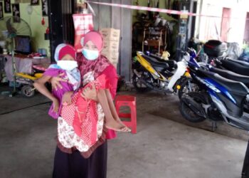 NORHANIS yang tidak mampu berjalan perlu didukung ibunya ketika ditemui di rumah mereka di Kampung Biah Perol, Kota Bharu.-UTUSAN/ ROHANA MOHD. NAWI