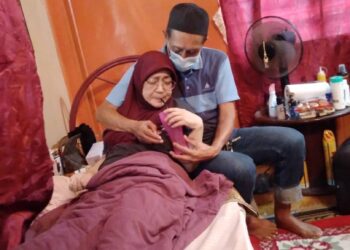 OMAR setia menjaga makan minum dan segala keperluan Che Hasnah selepas isterinya itu lumpuh di rumah mereka di Machang.-UTUSAN/ ROHANA MOHD. NAWI