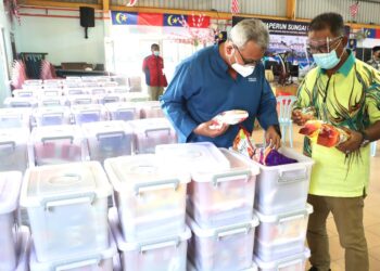 MOHD. REDZUAN Md. Yusof (kiri) bersama Idris Haron (kanan) melihat barangan keperluan harian pada majlis penyerahan kit makanan (Nadma) dalam tempoh Perintah Kawalan Pergerakan (PKP) bagi golongan terjejas di Parlimen Tangga Batu di Dewan Japerun Sungai Udang, Melaka. - UTUSAN/RASUL AZLI SAMAD