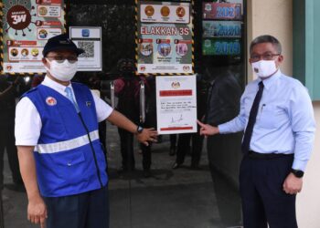 ADHAM Baba (kanan) bersama Dr. Sha’ari menunjukkan notis penutup kilang pemprosesan makanan di Taman Perindustrian Pulau Indah, Selangor hari ini.