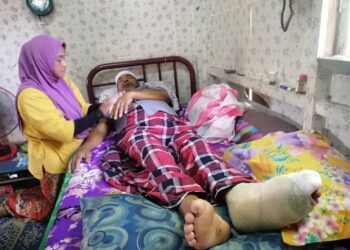 ABDULLAH yang terlantar selepas kakinya melecur dan membusuk akibat bertungku ditemani Hasnah di rumah mereka di Kampung Senawang Pulai Chondong, Machang. - UTUSAN/ROHANA MOHD NAWI