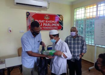 ROSOL Wahid (kiri) menyampaikan bantuan kepada penduduk terjejas Covid-19 di Pusat Khidmat Ahli Parlimen Hulu Terengganu di Kampung Bukit Tokbat, Hulu Terengganu. - UTUSAN/NOR HAYATI MAMAT