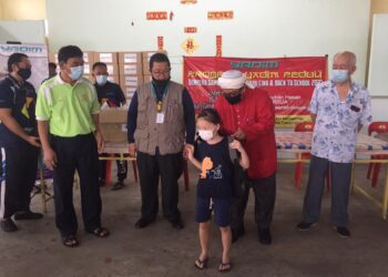 NASRUDDIN Hassan (dua dari kanan) menyarung beg sekolah kepada seorang kanak-kanak pada Program Yadim Peduli: Sumbangan Sempena Tahun Baharu Cina dan Kembali Ke Sekolah di Gambang, Kuantan, hari ini.