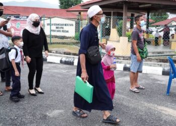 MOHD. Firdaus Nor Alauddin menghantar anaknya ke Sekolah Kebangsaan Meru Raya di Ipoh hari ini. - UTUSAN/ZULFACHRI ZULKIFLI