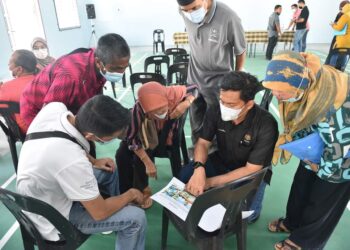 MOHD. SHAHAR Abdullah (dua dari kanan) menunjukkan pelan dan reka bentuk rumah RMR kepada peserta skim berkenaan.