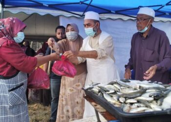 SYED Abu Hussin Hafiz Syed Abdul Fasal (dua dari kanan) menyerahkan ikan kepada penduduk pada program Kedai Bergerak di Dewan Orang Ramai Sungai Kerang, Trong di Bukit Gantang hari ini. - UTUSAN/WAT KAMAL ABAS