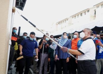 SAARANI Mohamad mengecat dinding dewan terbuka pada program gotong royong di Rumah Pangsa Conolly di Ipoh hari ini. - UTUSAN/ZULFACHRI ZULKIFLI