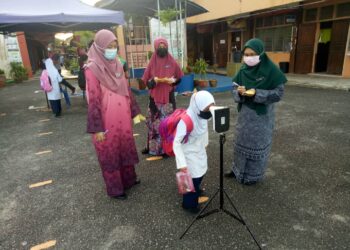 GURU Sekolah Kebangsaan Pasir Panjang di Kuala Terengganu mengambil suhu murid pada hari pertama sesi persekolahan secara bersemuka, hari ini.