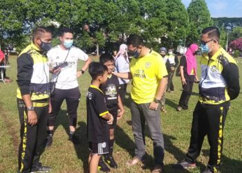 AHMAD Faizal Azumu (dua dari kanan) berbual dengan seorang pelatih Akademi Bola Sepak DRZ pada  pada program penyerahan dana kepada akademi itu di Tambun, Ipoh. - UTUSAN/SAYED HESHAM IDRIS