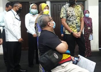 KHAIRY Jamaluddin (kanan) berbual dengan seorang penerima vaksin Covid-19 ketika melawat Pusat Pemberian Vaksin (PPV) Stadium Indera Mulia di Ipoh hari ini. - UTUSAN/SAYED HESHAM IDRIS