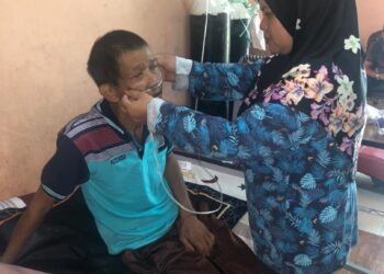 ROSIDAH Ahmad (kanan) membetulkan tiub pernafasan dipakai suaminya, Salamin Yusoff yang bergantung tangki oksigen di rumah mereka di Kampung SC, Kluang, Johor. -UTUSAN/ MOHAMAD FAHD RAHMAT