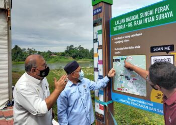 TUAN Ibrahim Tuan Man (tengah) melihat peta laluan basikal Sungai Perak Victoria-Kampung Raja Intan Suraya selepas menyempurnakan Majlis Perasmian dan Penyerahan PLSB Sungai Perak Fasa Satu 'Living River-Bike Trail dari Chenderoh ke Jambatan Victoria di Dataran Victoria di Sungai Siput hari ini. - UTUSAN/ASLIZA MUSA