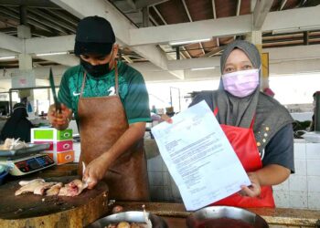 MADIHAH Mansor, 50, menunjukkan notis pengosongan Pasar Kuala Perlis oleh MPK ketika ditemui di Pasar Kuala Perlis hari ini.- UTUSAN/NAZLINA NADZARI