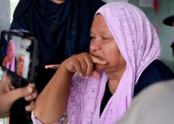 ZABIDAH A. Rahman, 60, setia menanti anaknya yang dikhuatiri lemas di Sungai Petuang, Tasik Kenyir di Hulu Terengganu hari ini. - PUQTRA HAIRRY ROSLI