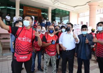 SULAIMAN Md. Ali (tengah) berswafoto dengan penghantar makanan Warong Rider selepas merasmikan platform dalam talian itu di Seri Negeri, Ayer Keroh, Melaka.