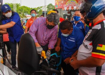 MOHAMAD Hasan mengisikan minyak seorang penunggang motosikal selepas menghadiri program Isi Minyak Percuma dan Santai Anak Muda serta Kempen Mari Daftar Vaksin Bersama Tok Mat anjuran Pemuda UMNO Bahagian Seremban di Sikamat, Seremban. - UTUSAN/MUHAMMAD IZZAT TERMIZIE