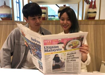 MINGYEONG Choi (kanan) bersama rakannya membaca Utusan Malaysia di Kuala Lumpur, kelmarin.