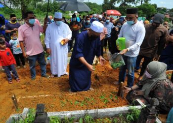 SUAMI kepada Noryati Taib, Hashim Mohd. Yusoff menyiram air mawar ke atas pusara isterinya  yang merupakan seorang pelakon di Tanah Perkuburan Kampung Kurnia, Kebun Teh di Pasir Gudang, Johor. -UTUSAN/RAJA JAAFAR ALI