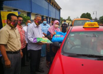 RODZIAH Ismail (kanan) menyampaikan sumbangan barang makanan dari Food Bank Malaysia kepada pemandu teksi di Dewan Seri Jugra, Teluk Datuk, Banting, Selangor. UTUSAN/ABDUL RAZAK IDRIS