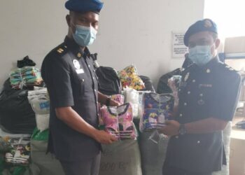 PEGAWAI penguat kuasa KPDNHEP memeriksa dan menunjukkan barang tiruan iaitu pakaian pelbagai jenama dalam serbuan dua buah premis yang dijadikan stor penyimpanan barang tiruan di Bandar Enstek, Seremban, semalam.