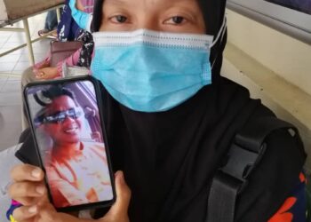 ROSMAWATI Hussin, 41, menunjukkan gambar suaminya yang maut daalam kemalangan dengan sebuah lori di Kilometer 107, Jalan Kuala Terengganu-Kuantan di Kemaman  hari ini. -NIK NUR IZZATUL HAZWANI NIK ADNAN