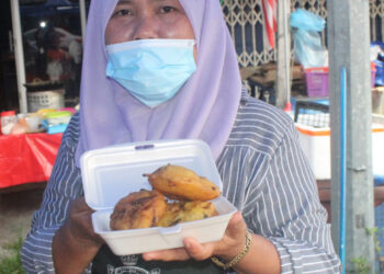 NORASHIKIN Ahmad atau Mak Kedah menunjukkan Cucur Udang Super yang dijualnya di Pekan Kayu Ara Pasong, di Pontian, Johor.  - UTUSAN/MUHAMMAD ZIKRI